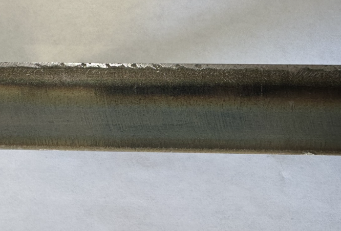 Metal with a heat-affected-zone from heat-based cutting, showing discoloration near the edge.